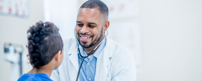 Male doctor listening to heart with stethoscope of child patient